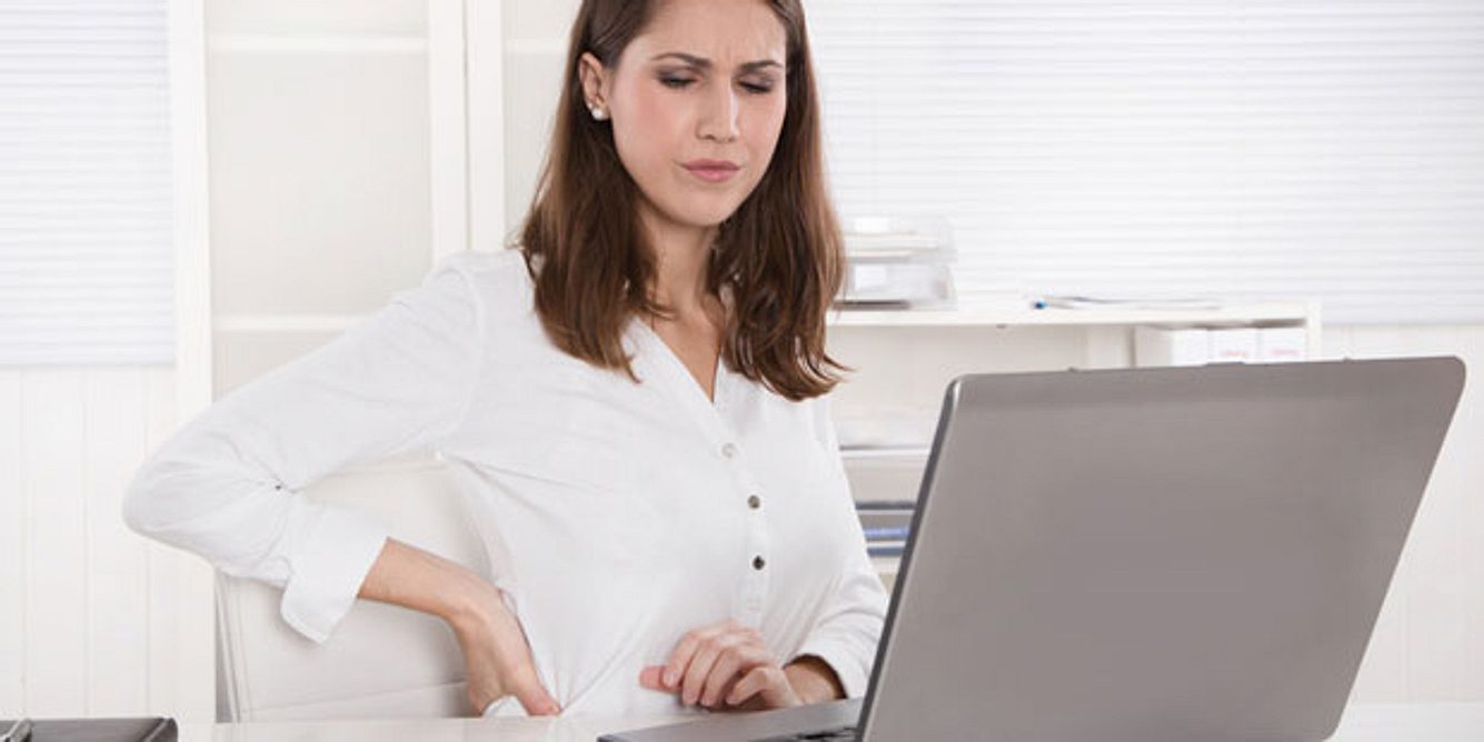 Frau mit Rückenschmerzen im Büro