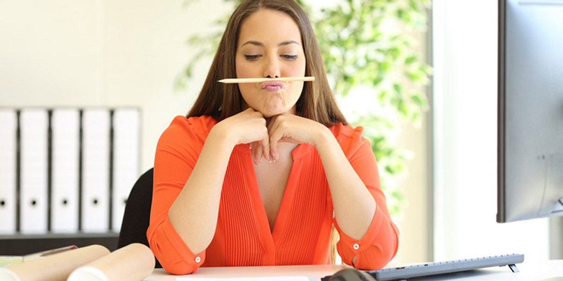 Aus Langeweile balanciert eine Frau einen Stift auf ihren Lippen