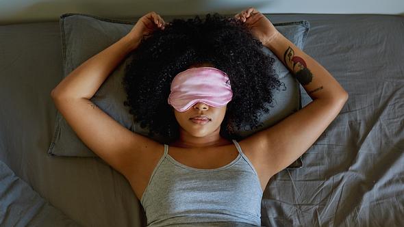 Frau mit Schlafmaske im Bett - Foto: iStock/LaylaBird