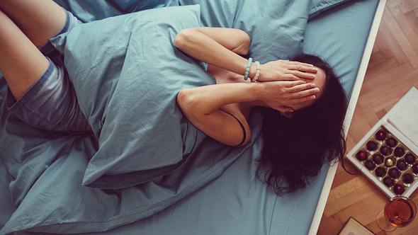 Frau liegt weinend im Bett - Foto: iStock/martin-dm