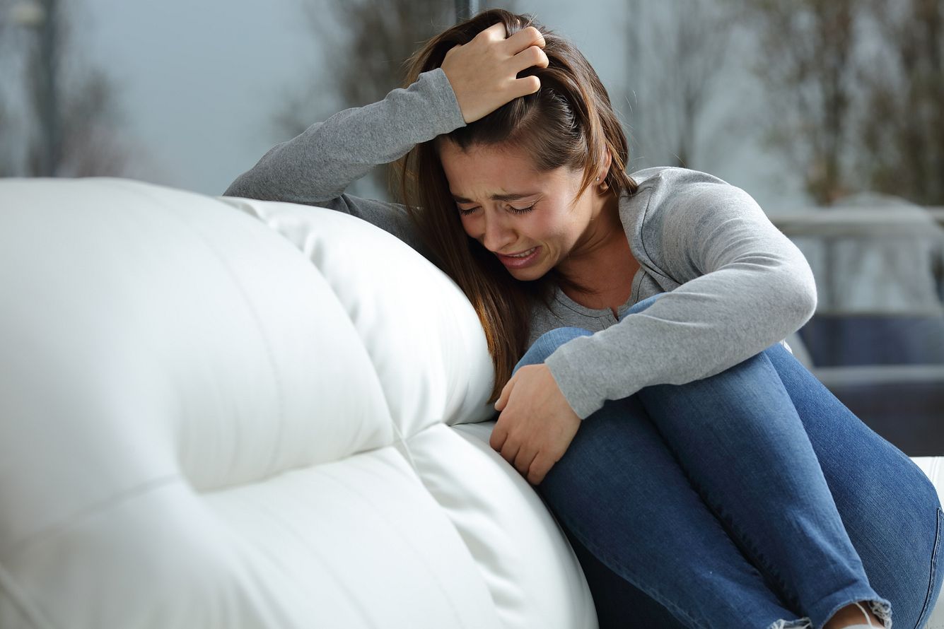 Mädchen weint alleine auf dem Sofa