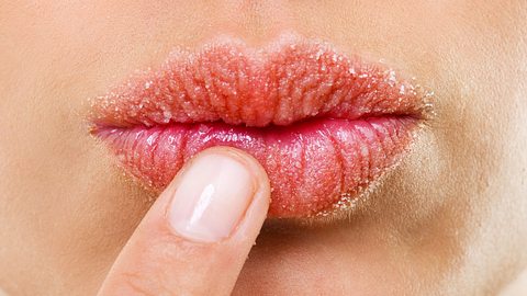 Ein Finger fässt sich an die Lippen, auf denen ein Peeling aufgetragen ist - Foto: istock_PeopleImages