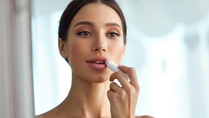 Frau trägt sich eine Pflege auf die Lippen auf - Foto: istock_puhhha
