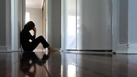 Eine Frau mit Long Covid sitzt erschöpft auf dem Boden - Foto: iStock/chameleonseye