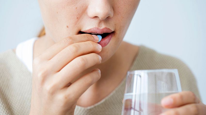 Frau nimmt eine Tablette ein und hält ein Glas Wasser in der Hand - Foto: iStock/seb_ra