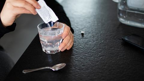 Eine Frau rührt Trinkgranulat in ein Glas Wasser - Foto: iStock/die-phalanx