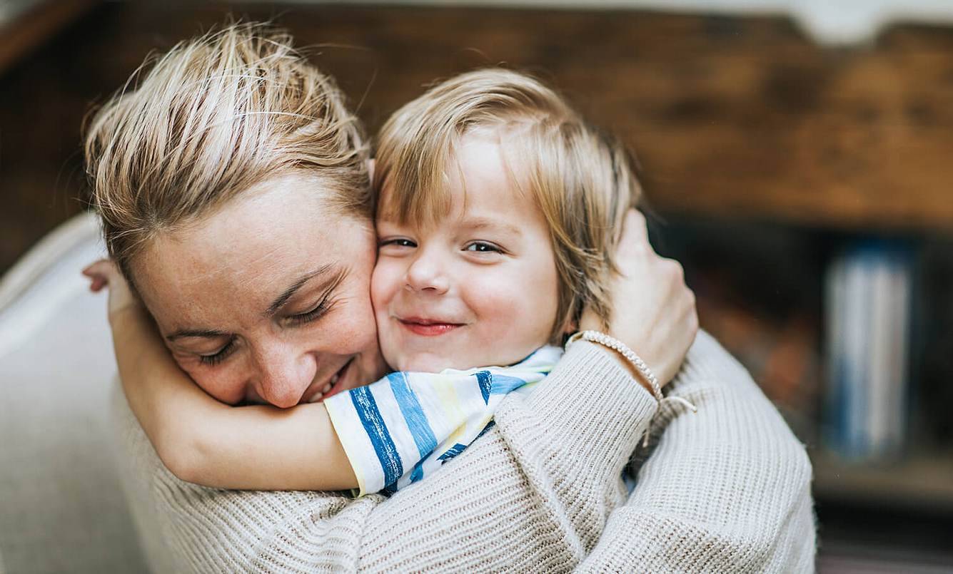 Eine Mutter umarmt ein kleines Kind und lacht