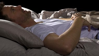 Ein Mann liegt im Bett - Foto: Shutterstock
