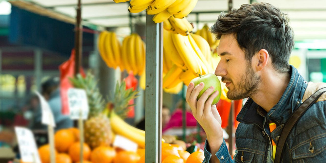 Mann riecht an Apfel