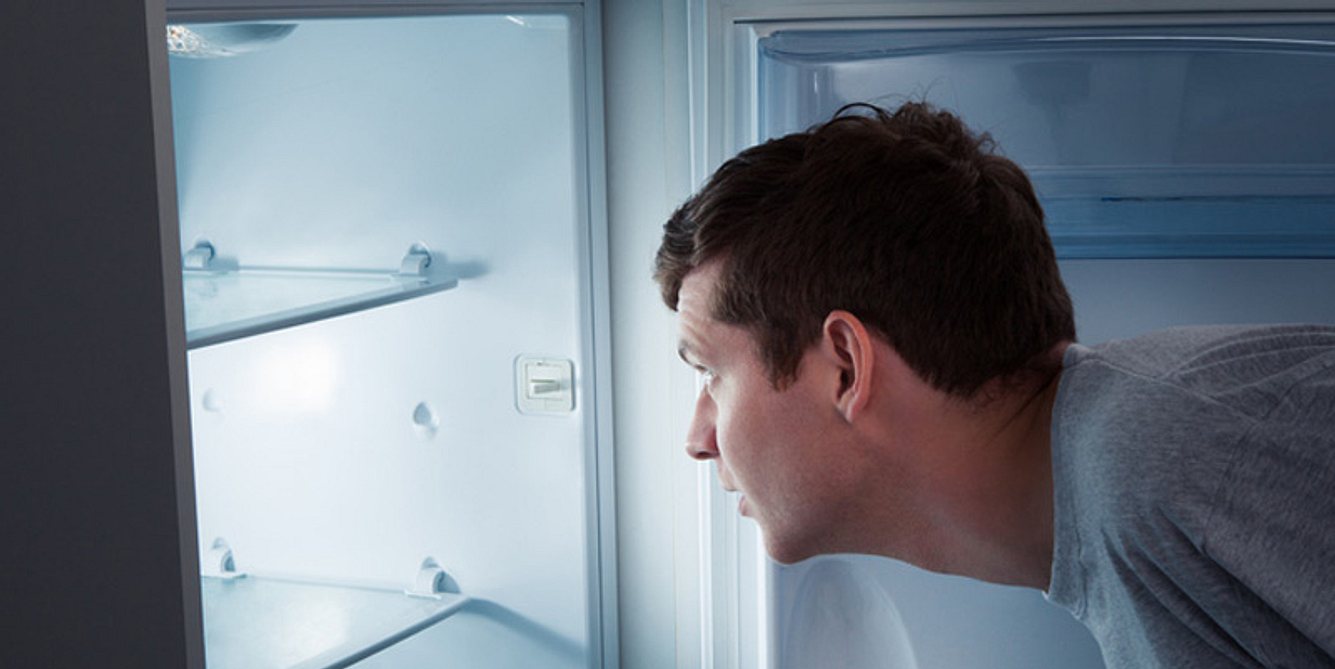 Mann steht vor leerem Kühlschrank