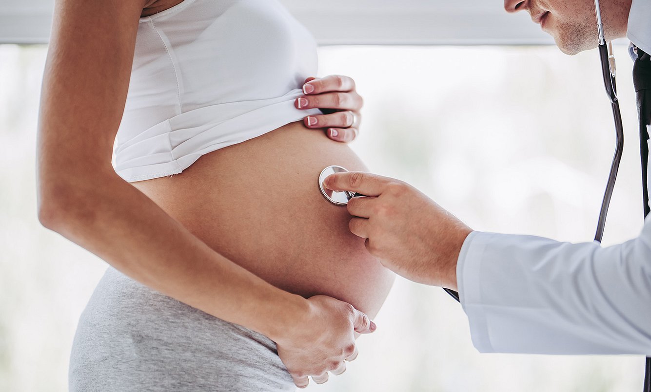 Ein Arzt untersucht eine schwangere Frau mit einem Stethoskop