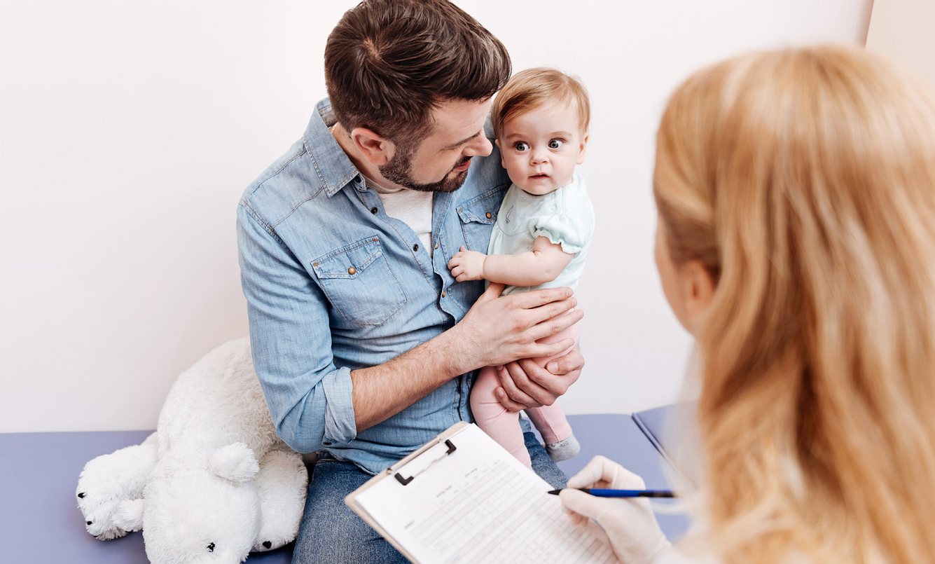 Ein Vater ist mit seinem kleinen Kind bei der Kinderärztin