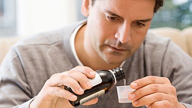 Mann nimmt Hustensaft - Foto: Alamy