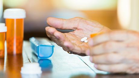 Ein Mann legt Tabletten in seine Hand - Foto: iStock/SDI Productions