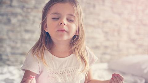 Mädchen meditiert im Bett - Foto: iStock/Liderina