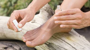 Frau lackiert sich die Fußnägel mit medizinischem Lack - Foto: imago