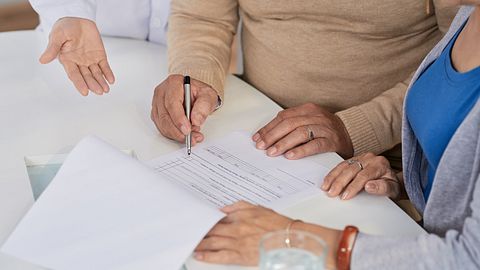 Ehepaar unterschreibt Dokument beim Arzt - Foto: iStock/DragonImages