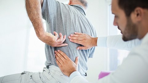 Mann hält sich den Rücken - Foto: iStock/gilaxia