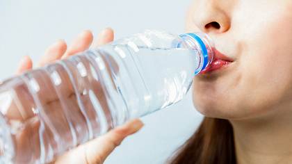 Eine Frau trinkt Wasser aus einer Plastikflasche - Foto: iStock/metamorworks