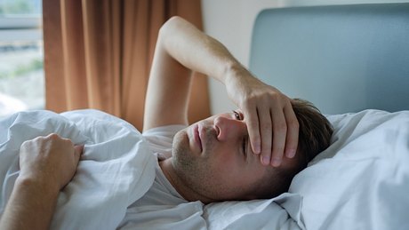 Mann hat milden Omikron-Krankheitsverlauf und liegt im Bett - Foto: iStock/Koldunova_Anna