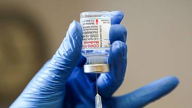 Eine Nahaufnahme einer Person, die mit blaune Handschuhen eine Corona-Impfdosis vorbereitet - Foto: IMAGO_ZUMA Wire