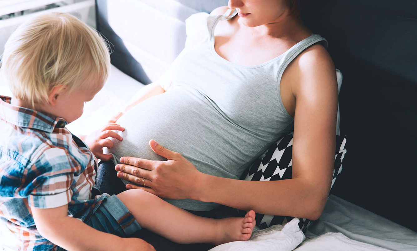 Kleinkind fühlt den Bauch seiner schwangeren Mutter – SSW 20