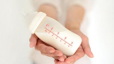 Person hält Flasche mit Muttermilch in der Hand - Foto: istock/aliseenko