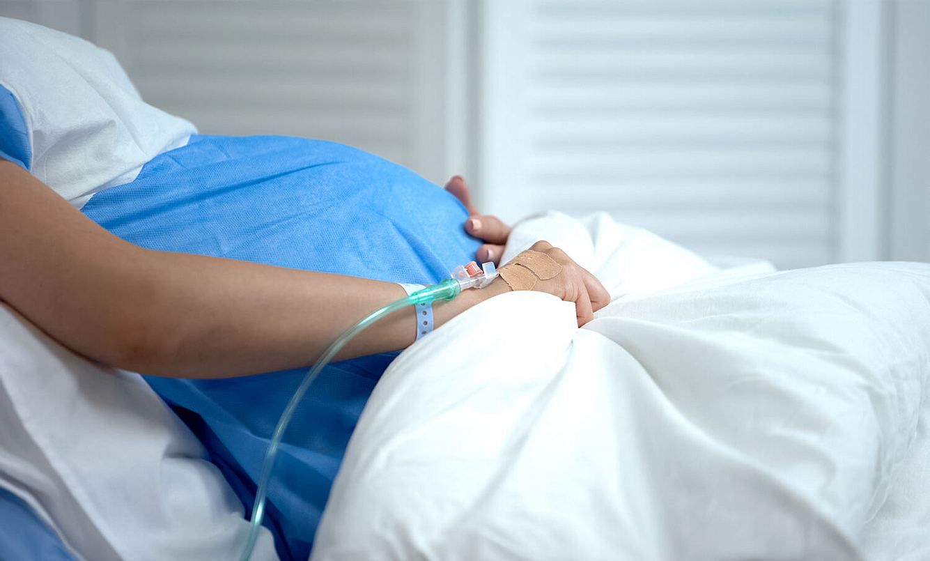 Schwangere Frau liegt im Krankenbett