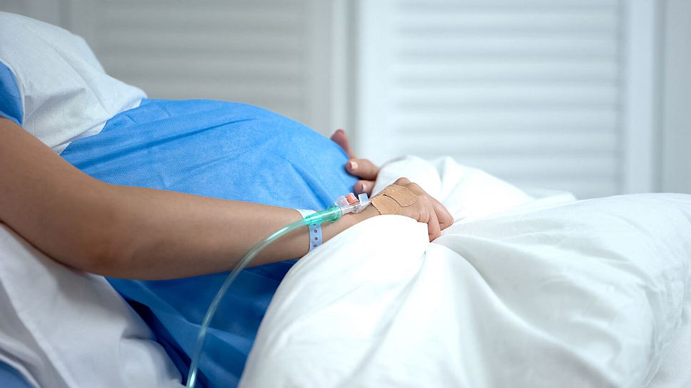 Schwangere Frau liegt im Krankenbett - Foto: iStock/motortion