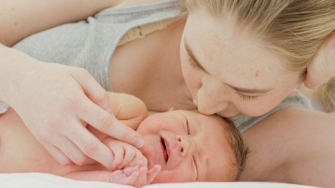 Mutter küsst Neugeborenes auf den Kopf - Foto: iStock/FatCamera