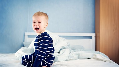 Junge mit Nachtschreck sitzt in seinem Bett und weint - Foto: iStock/LeManna