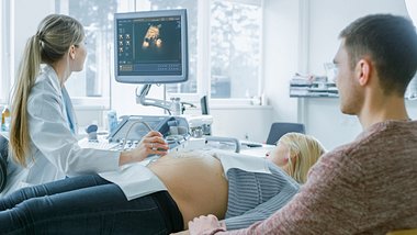 Schwangere mit Partner zur Nackenfaltenuntersuchung beim Ultraschall - Foto: iStock/gorodenkoff