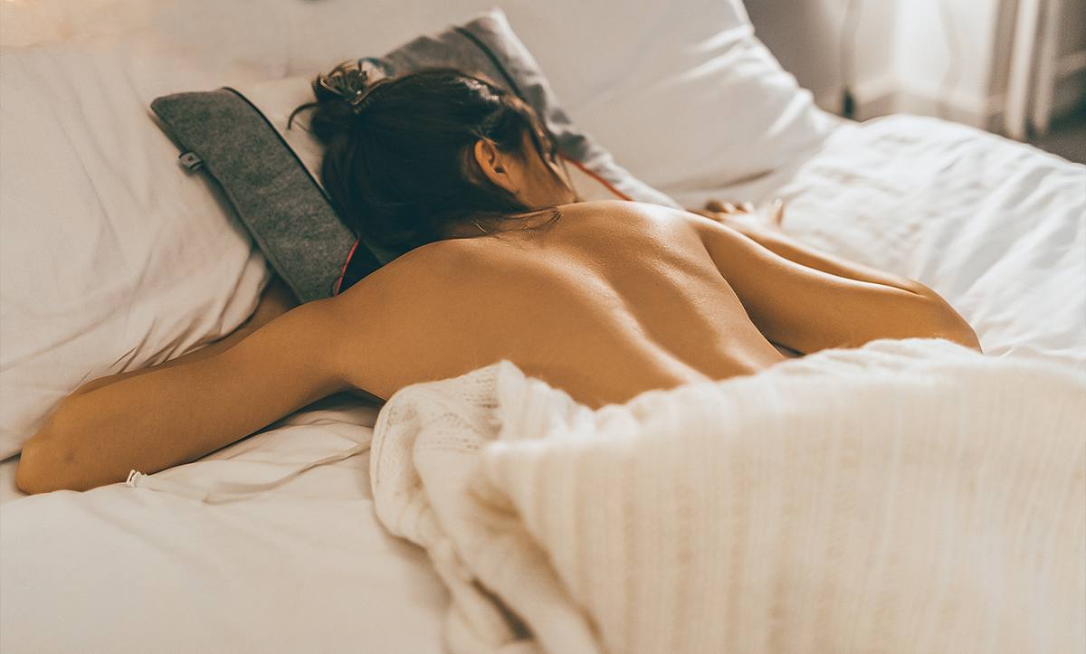 Eine Frau schläft nackt im Bett