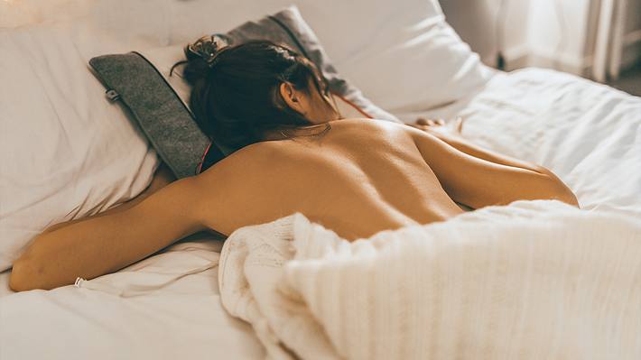 Eine Frau schläft nackt im Bett - Foto: iStock/Jecapix