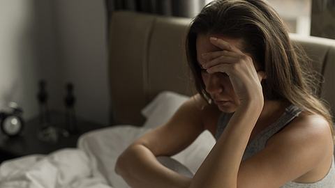 Eine Frau sitzt nachts wach in ihrem Bett - Foto: iStock/bymuratdeniz