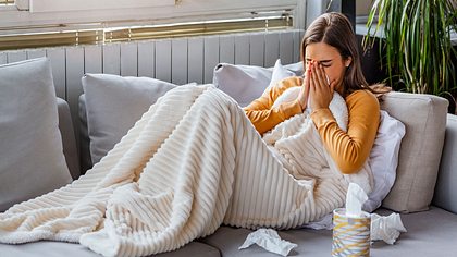 Frau liegt krank auf dem Sofa. - Foto: iStock/stefanamer