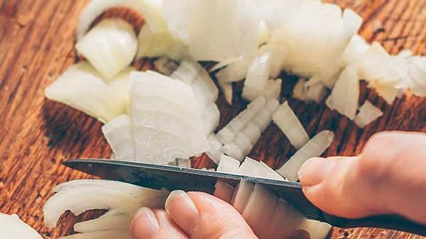 Person schneidet eine Zwiebel mit dem Messer - Foto: iStock/andreygonchar