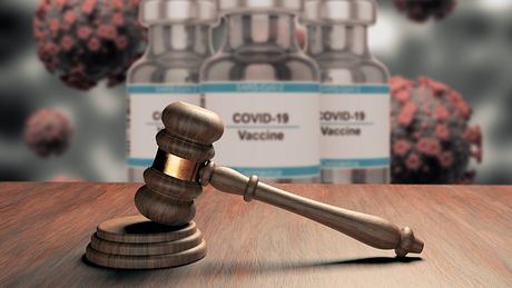 Richterhammer mit Coronavirus-Impfstoff im Hintergrund - Foto: iStock/Gilnature