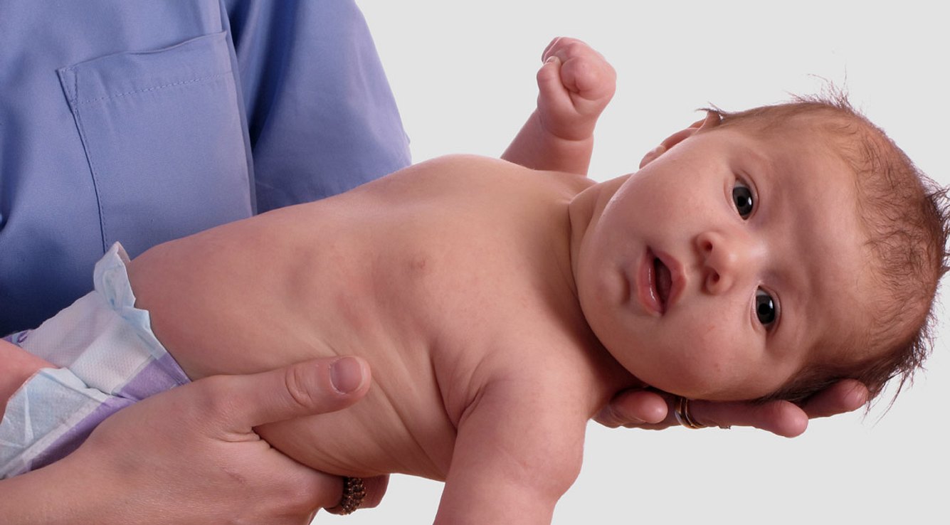 Ein Arzt hält ein Neugeborenes im Arm