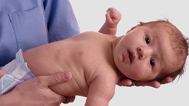Ein Arzt hält ein Neugeborenes im Arm - Foto: Alamy