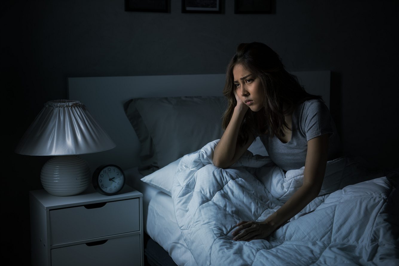 Eine Frau sitzt mit Schlafproblemen im Bett