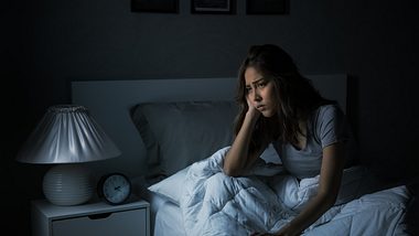 Eine Frau sitzt mit Schlafproblemen im Bett - Foto: iStock_amenic181