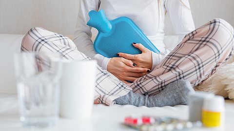 Am Norovirus erkrankte Frau mit Wärmflasche auf dem Bauch - Foto: grinvalds