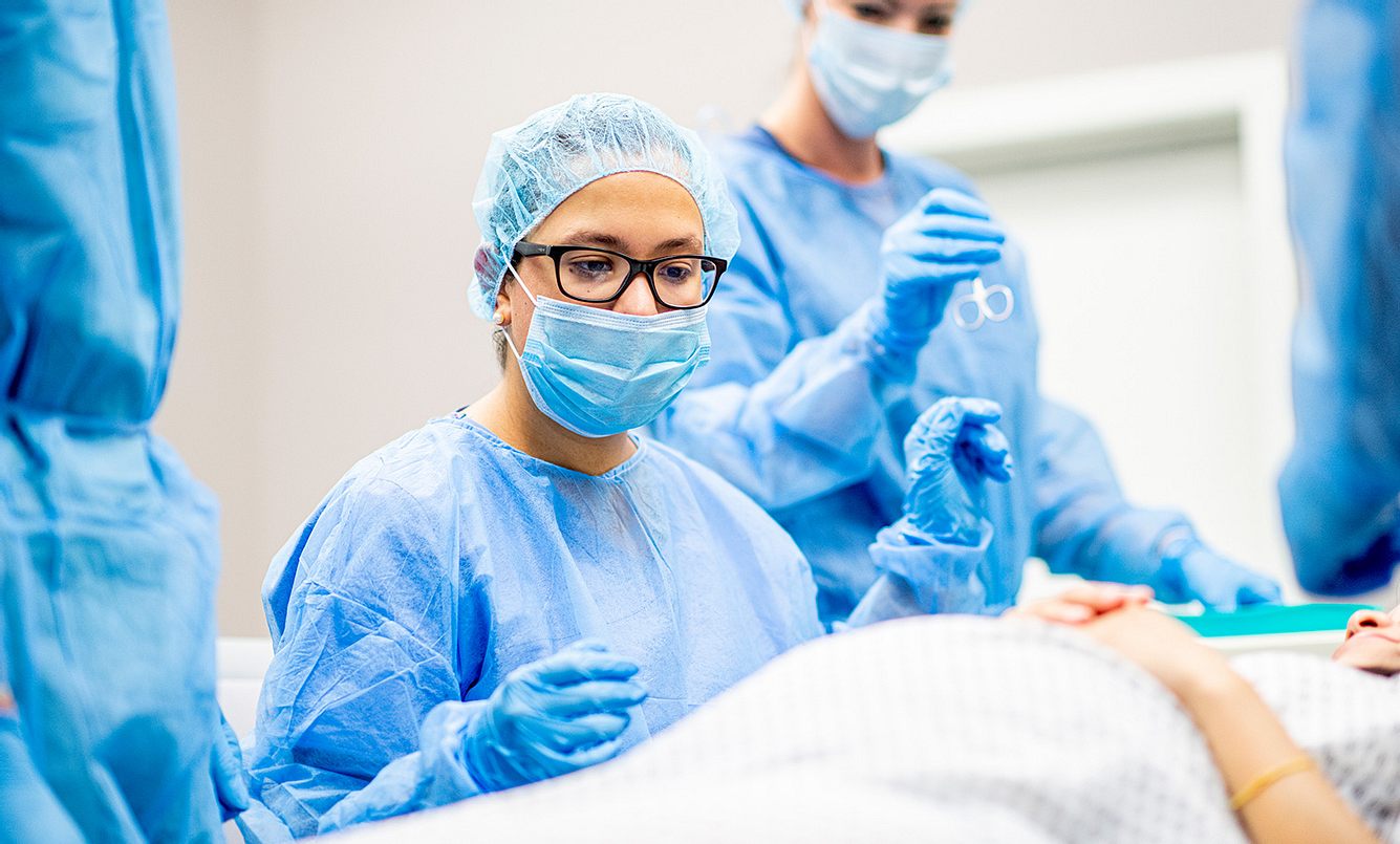 Schwangere befindet sich im OP-Saal während Ärzte und OP-Assistenten den Notkaiserschnitt durchführen