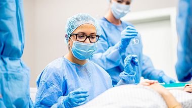 Schwangere befindet sich im OP-Saal während Ärzte und OP-Assistenten den Notkaiserschnitt durchführen - Foto: iStock/FatCamera