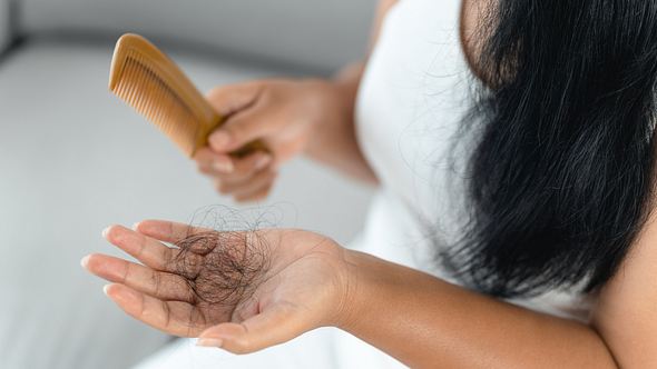 Eine Frau hat einen Büschel Haare in ihrer Hand, nachdem sie ihre Haare gekämmt hat - Foto: iStock/Suriyawut Suriya