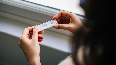 Person hält positiven Corona-Schnelltest in der Hand - Foto: Istock/agrobacter