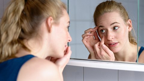 Junge Frau schaut in den Spiegel - Foto: mheim3011/iStock