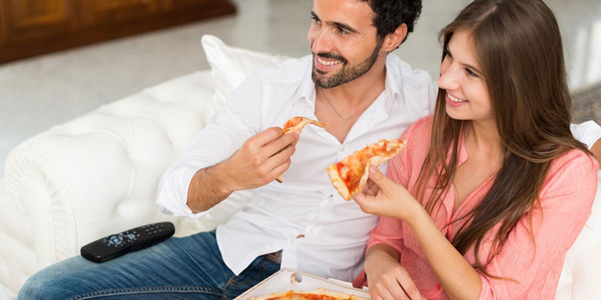 in Paar isst Pizza auf einer Couch