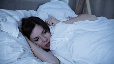 Eine Frau hat eine Panikattacke nachts im Bett - Foto: iStock/AndreyPopov